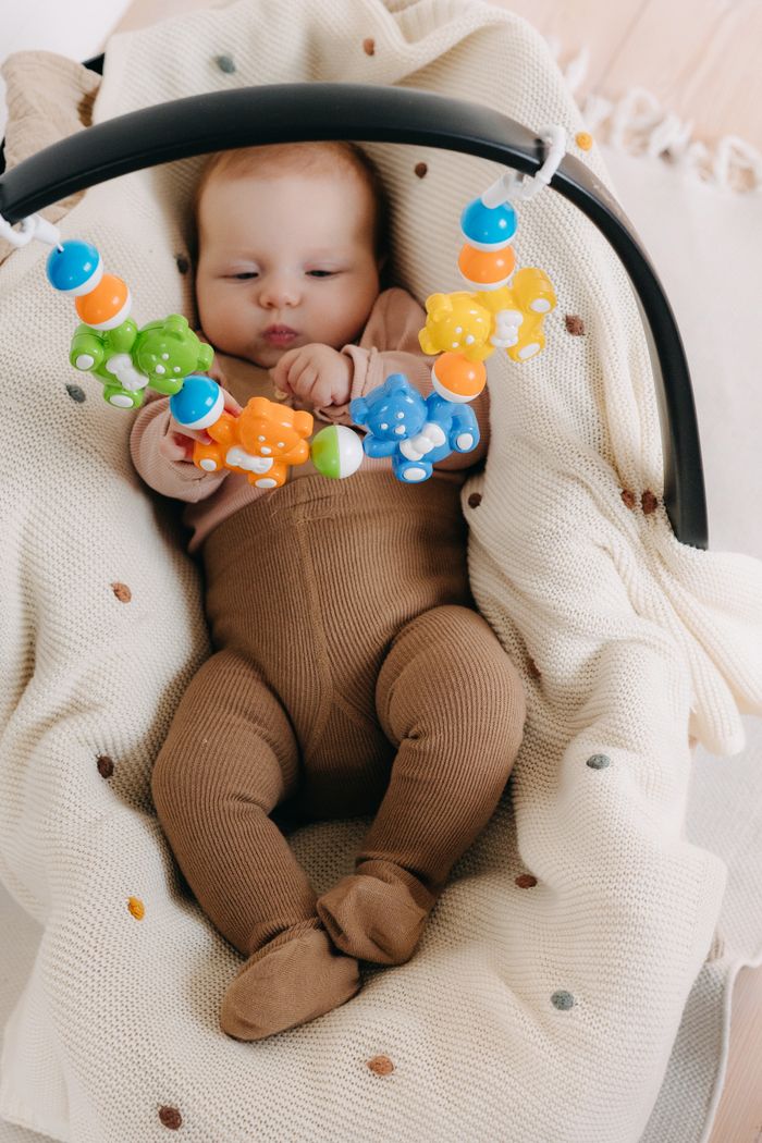 Services Adorable baby enjoying playtime with vibrant toys on a soft blanket indoors.